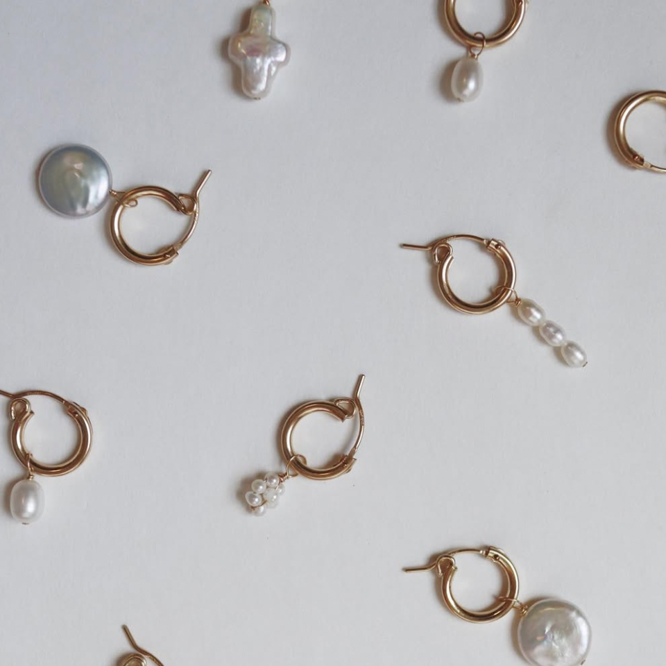 Gold hoop earrings with pearls on a white background